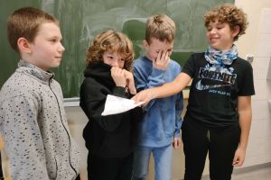 Czterech chłopców ze swoja prezentacja przy tablicy