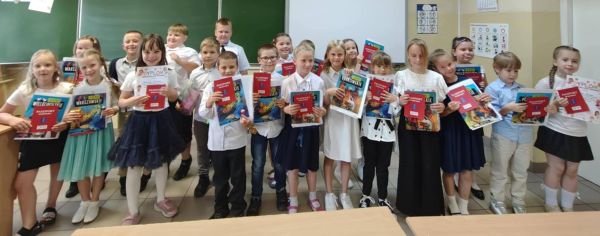 Grupa dzieci stoi trzymając Paszporty Sportowe