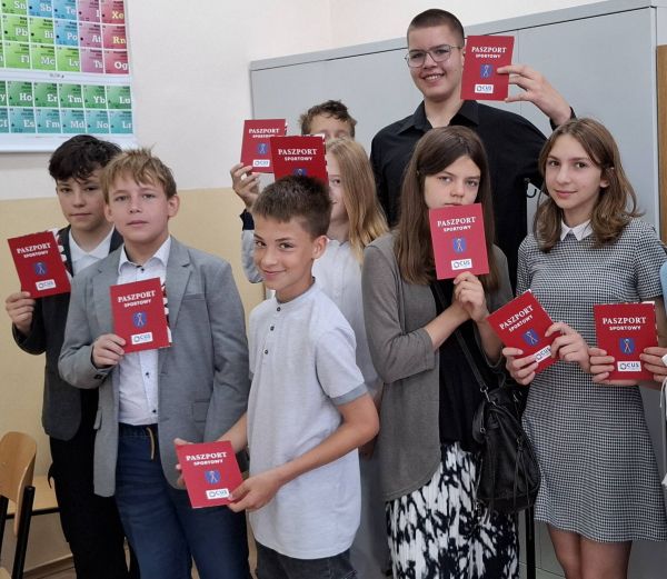 Grupa dzieci stoi z Paszportami Sportowymi w rękach