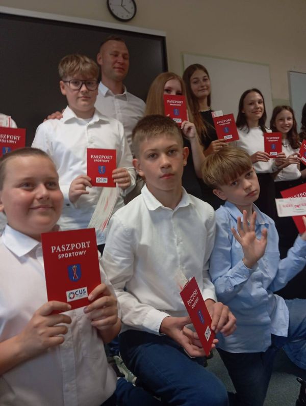 Grupa dzieci stoi z Paszportami Sportowymi w rękach