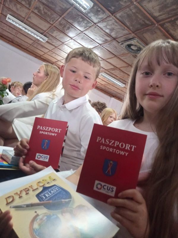 dziewczynka i chłopiec siedzą z Paszportami Sportowymi w ręku