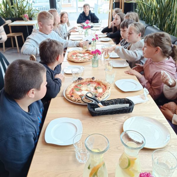 Grupa dzieci przy stole z pizza