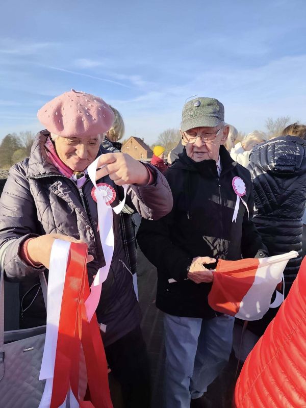 Seniorzy wieszają biało czerwone wstążki na moście