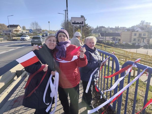 Seniorzy na moście z flagami Polski