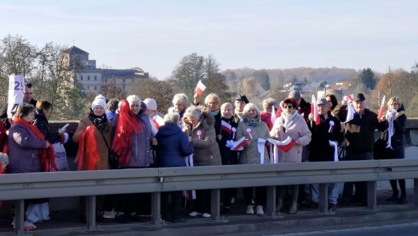 Seniorzy na moście z flagami Polski