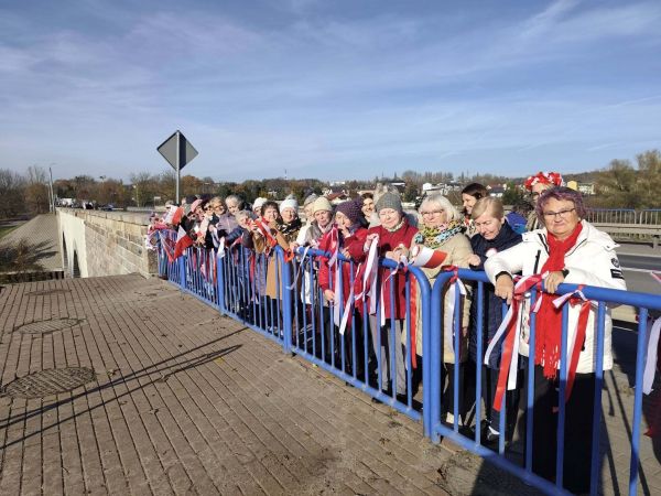 Seniorzy na moście z flagami Polski